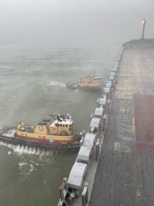 Photo of tugboats holding ship in place during storm
